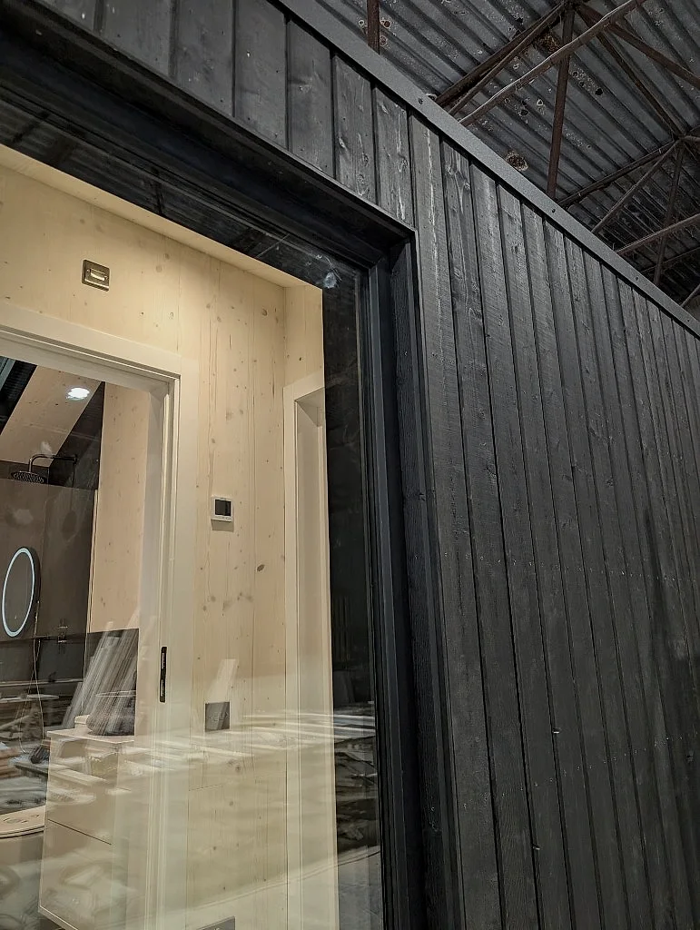 Charred timber cladding and window detail of the first lodge in the factory